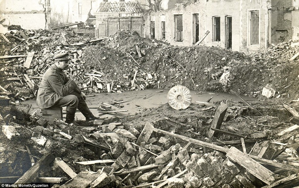 A soldier sits in the debris of destroyed buildings at the edge of a huge crater. The walls of the buildings have crumbled and roofs fallen down in a scene synonymous with The Great War which ravaged Europe between July 28, 1914 to November 11, 1918