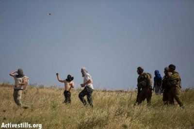 Settlers attack village residents as the Israeli army stand by . Photo: Activestills