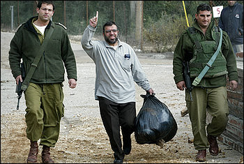 Sheik Hassan Yousef, center, a founder of Hamas, was escorted by Israeli army soldiers out of a military jail near the West Bank town of  Ramallah, in this Nov. 18, 2004, file photo. His son, Mosab Hassan Yousef, writes in a new memoir that he fed secrets about Hamas to Israelis.