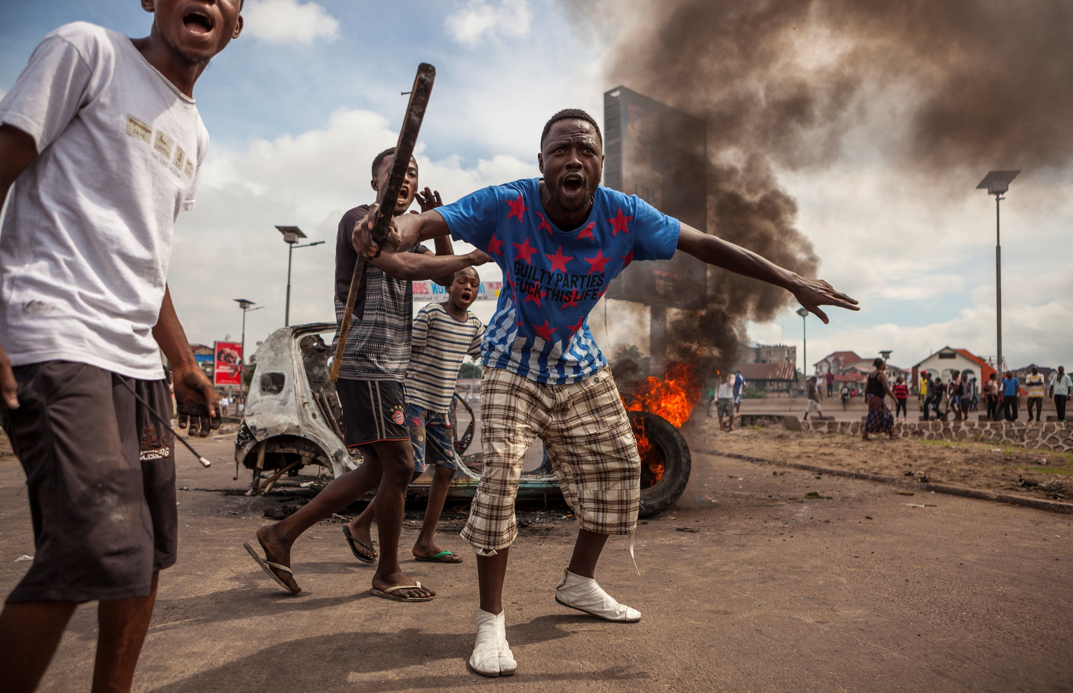 Demonstrators gather in front of a burning car during an opposition rally in Kinshasa