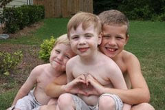 Three boys with one making a heart shape with his hands