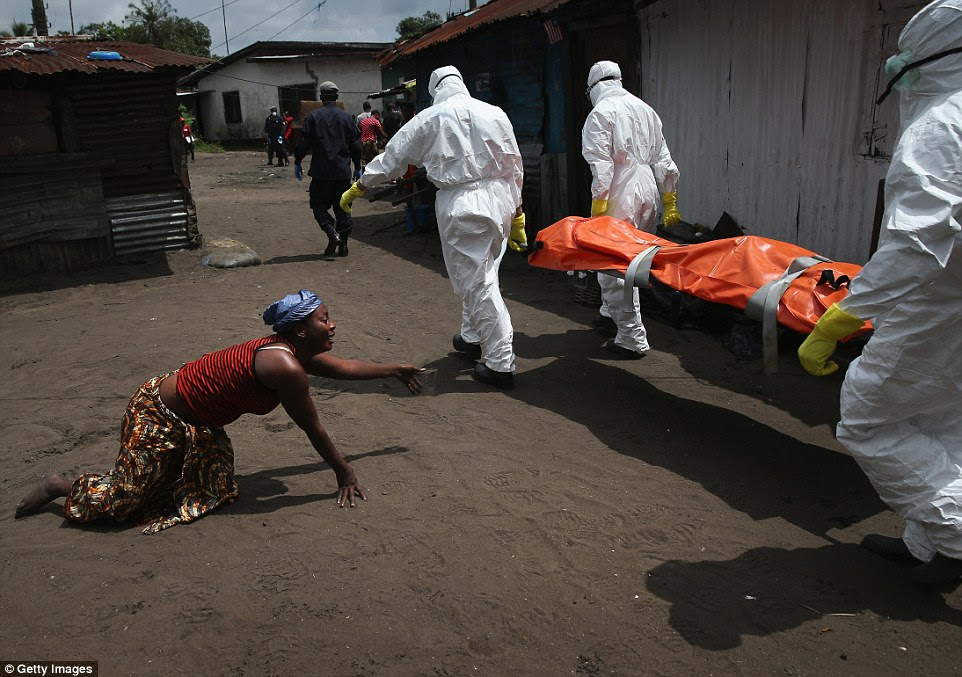 Grief-stricken: These photos, taken by photographers John Moore and Mohammed Elshamy, show the grim reality of the Ebola outbreak in Liberia, West Africa. Above, a woman crawls toward the body of her sister as an Ebola burial team takes it away for cremation