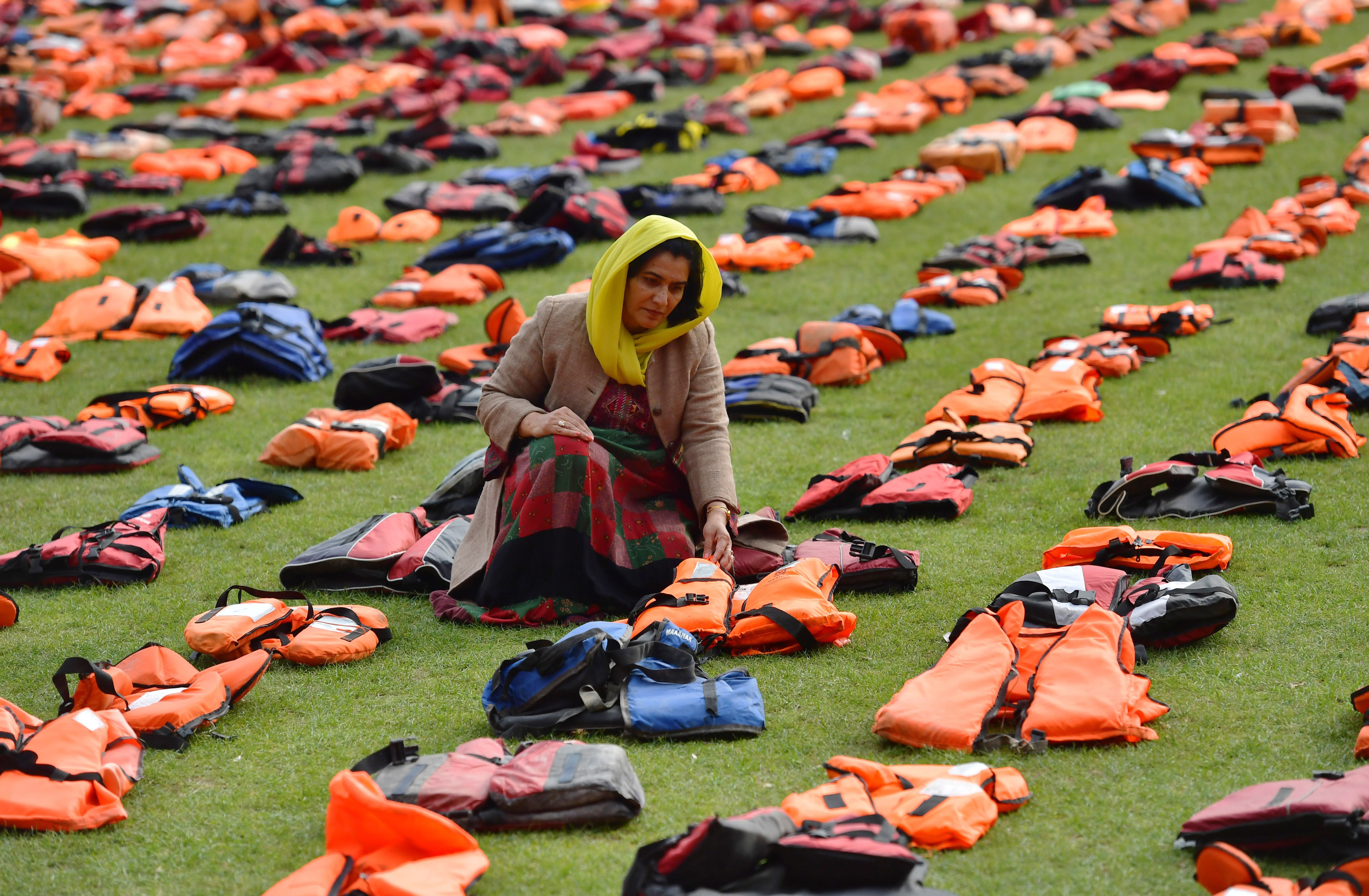 Rahela Sidiqi, a trustee of Women for Refugee Women and originally from Afghanistan, poses for a photograph among lifejackets that have been used by refugees to cross the sea to Europe as they are laid out in Parliament Square