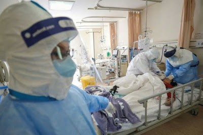Imagem de profissionais de saúde atendendo paciente de covid-19 num leito hospitalar
