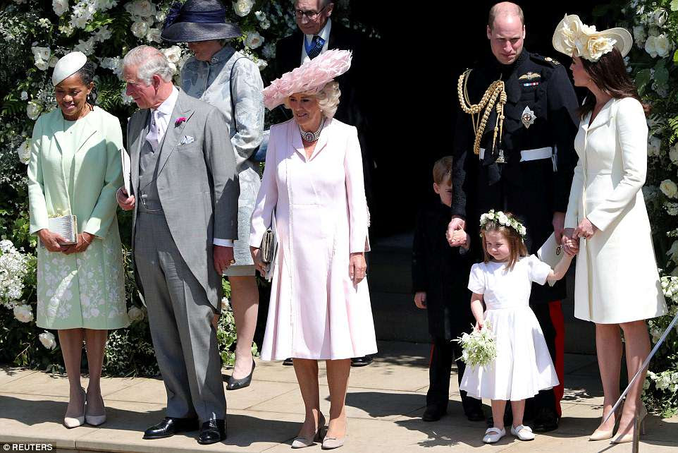 Princess Charlotte is pictured second left with her mother Kate and father William as her brother George hides behind his legs outside St George's Chapel in WindsorÂ