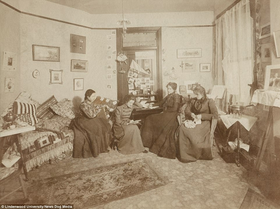 Four women, in floor length, high necked dresses sit in a dorm room in Lindenwood University, St Charles, Missouri in the late 19th century 