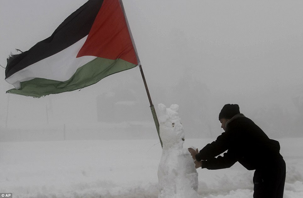A Palestinian security officer puts the finishing touches to his snowman decorated with a Palestinian flag in the West Bank city of Hebron