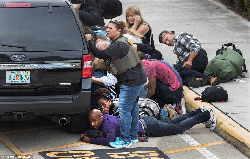 People take cover at the Ft. Lauderdale Airport after a gunman killed 5 people and injured many more
