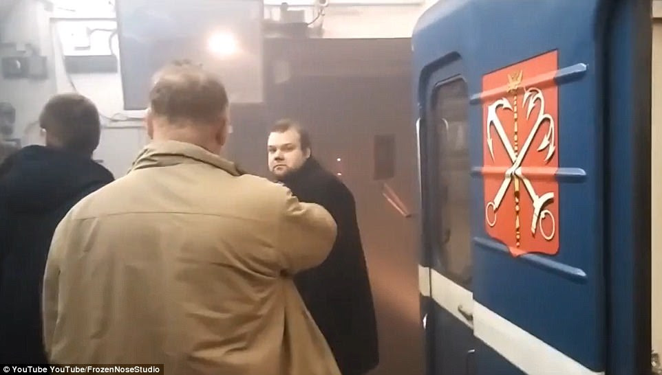 Three men walk away from the train in a smoke-filled subway station after a huge blast from a suspected nail bomb