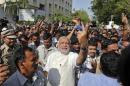 Hindu nationalist Modi shows his ink-marked finger to his supporters after casting his vote in Ahmedabad