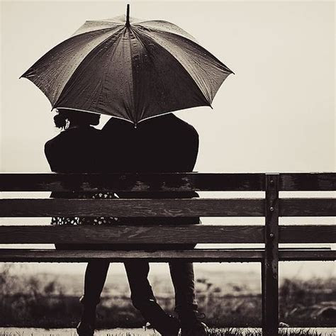 Couple sitting on a bench in the rain with umbrella Couple sitting on a bench in the rain with umbrella
