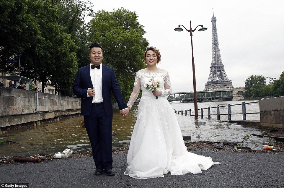 Wet wedding: An Asian couple proved the extreme weather was unable to prevent the course of true love after they tied the knot in Paris today