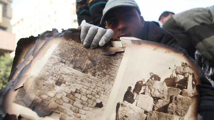 A worker displays pages from the ancient document "Le Description de L'Egypt" salvaged from the ruins 