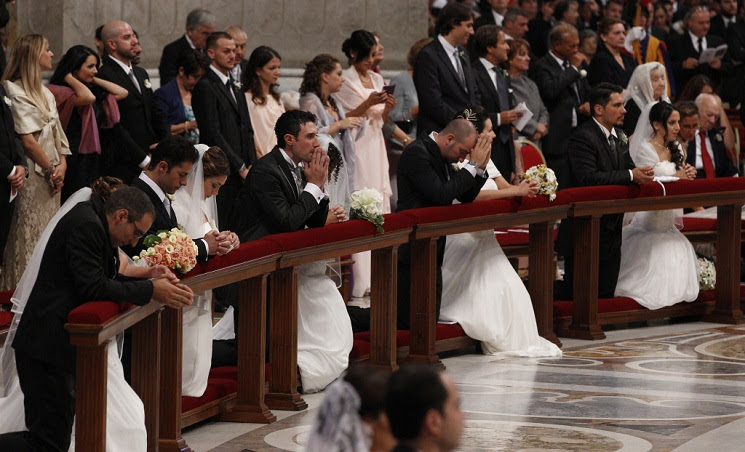 Newly married couples kneel as Pope Francis celebrates marriage rite for 20 couples during Mass at Vatican