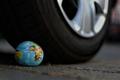 Foto retangular do pneu de um carro "atropelando" um globo terrestre