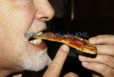 man taking a bite of pizza