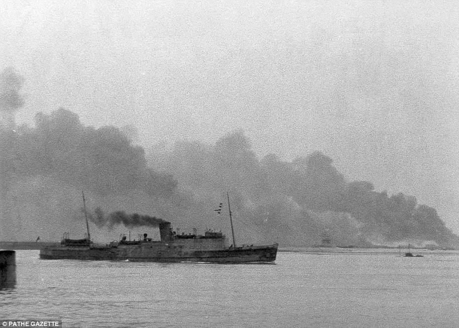 A ship laden with troops sets off for home as Dunkirk burns in the background