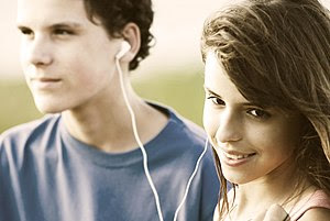 Teens sharing earphones, listening music outdo...