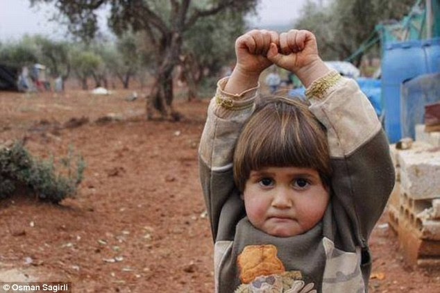 Harrowing: Taken at the Atmen refugee camp on Syria's border with Turkey, the image shows four-year-old Adi Hudea frozen in fear with her arms raised and her lips tightly pursed
