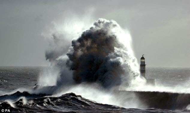 Threatening: A lighthouse is dwarfed by a stormy wave as fierce winds hit Seaham Harbour, County Durham