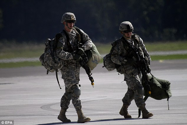 Two US soldiers carry their kit across the air base as they arrive for yesterday's exercise