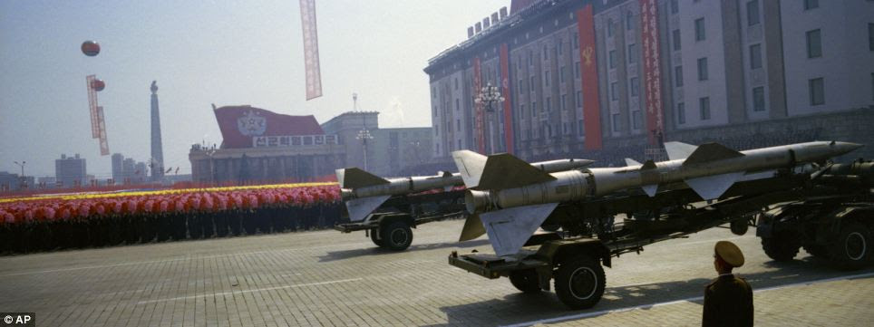 Tradition: Rockets roll past flower waving civilians and a soldier standing at attention during a mass military parade in Pyongyang's Kim Il Sung Square