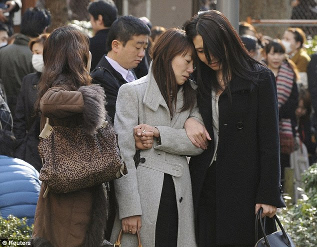 Emotional: Two visibly shaken young Japanese women who were evacuated from a building in Central Park in Tokyo comfort each other as news spreads of the devastation unleashed across the country