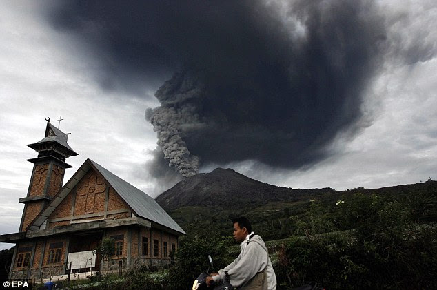 Ash: A resident attempts to escape from his village on a moped as the volcano erupts in the background