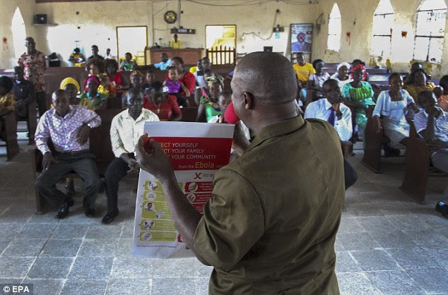 Orientação: Um liberiano trabalhador de campo Unicef lê uma informação cartaz Ebola na prevenção da epidemia de Ebola, durante uma reunião na Missão para hoje Santa Igreja, em Newkru Town, Monrovia, Libéria