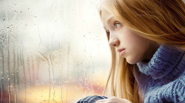 Rainy Day: Girl looking through the Window