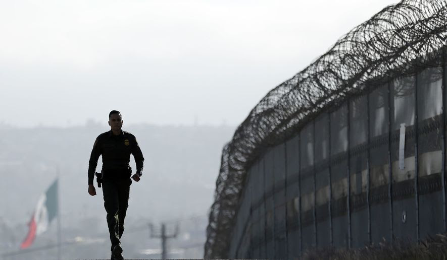FILE - In this June 22, 2016, file photo, Border Patrol agent Eduardo Olmos walks near the secondary fence separating Tijuana, Mexico, background, and San Diego in San Diego. The number of immigrants in the U.S. illegally has changed little since the Great Recession began, dropping to 11.1 million in 2014 from 11.2 million in 2012 and 11.3 million in 2009, according to a study released Tuesday, Sept. 20, 2016, by the Pew Research Center. (AP Photo/Gregory Bull, File)