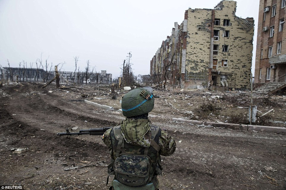 On guard: A separatist soldier stands close to a ruined hotel in Donetsk as weapons were moved away from the front line