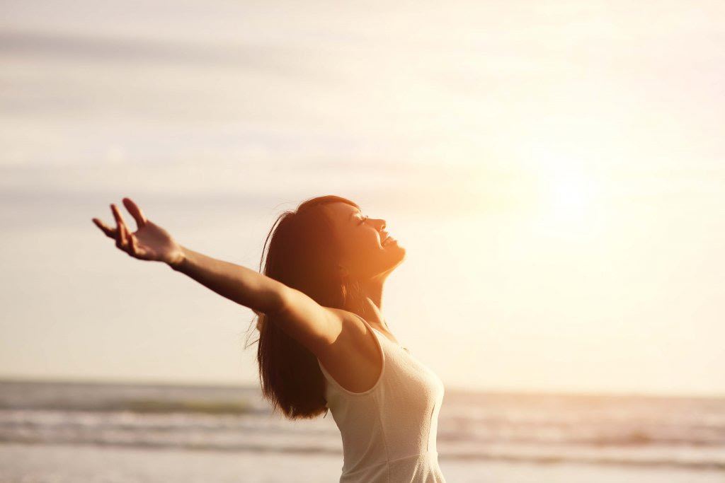 Mujer positiva abriendo los brazos para recibir al amanecer