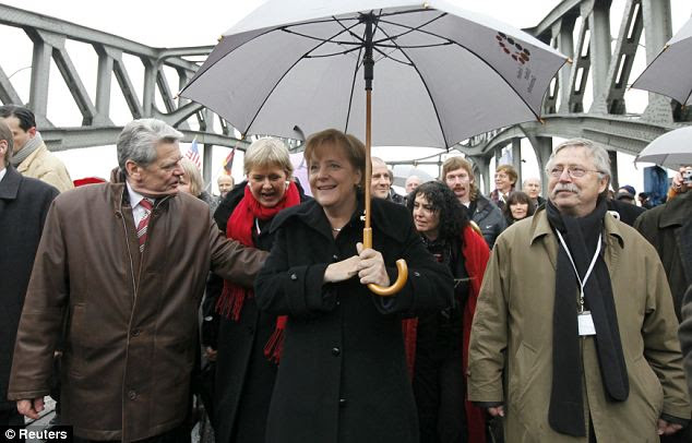 German Chancellor Angela Merkel (c) walks across the Bornholmer Strasse Bridge today, retracing her steps from East Germany 20 years ago