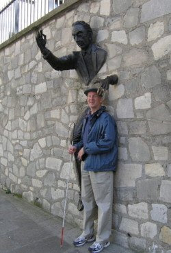 Mike standing with his head cradled by the Bronze man