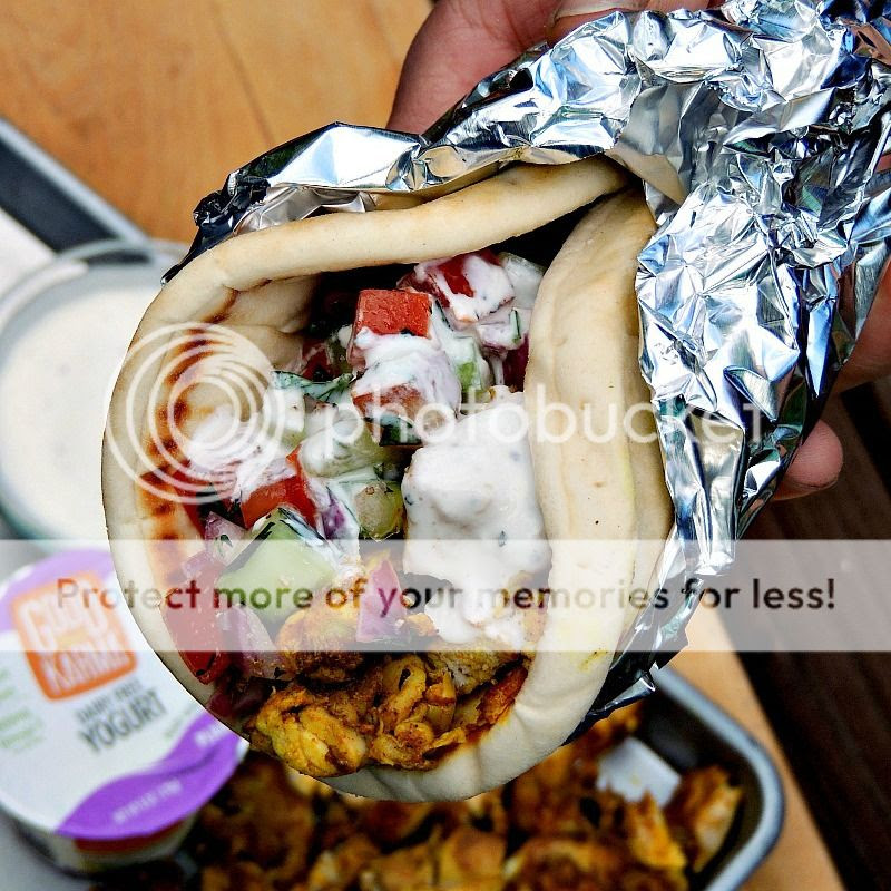Close up of someone holding a Sheet Pan Chicken Shawarma sandwich wrapped in foil.