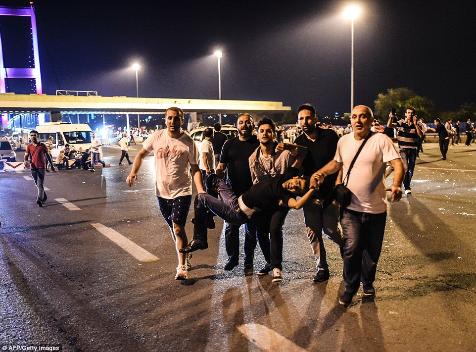 Unarmed civilians carried a man believed to have been shot by Turkish troops away from the Bosphorus bridge in Istanbul 