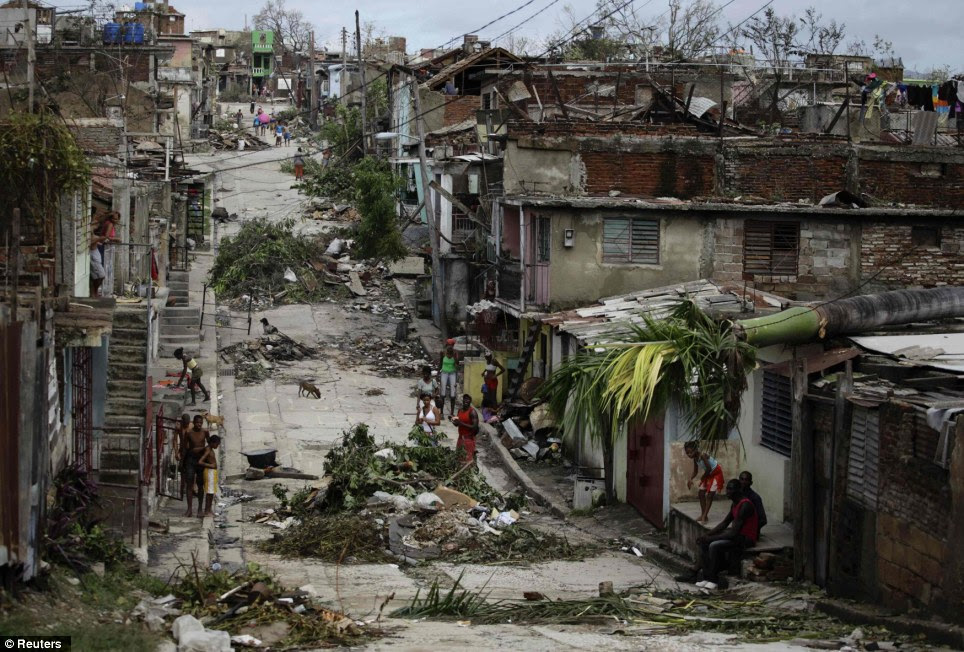Sandy's Path of Destruction: People walk on a street littered with debris after Hurricane Sandy hit Santiago de Cuba last week