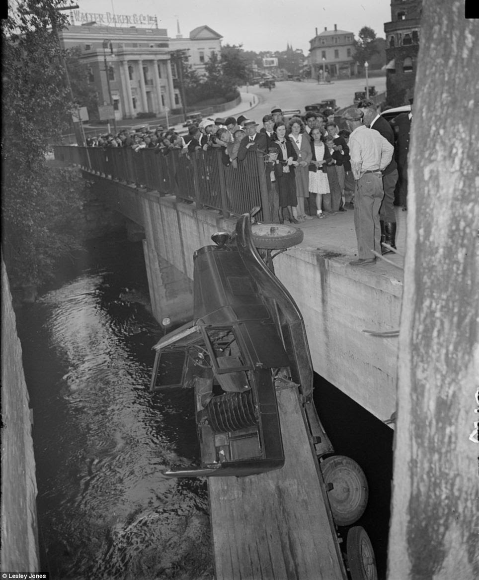 Taken in 1934, this photograph shows a truck balancing on a bridge in Dorchester by just one wheel. Workers from the Walter Baker & Co chocolate factory rushed out of the building in the background to watch