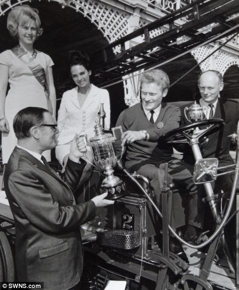 Michael Banfield sitting in the Merryweather appliance receiving a trophy