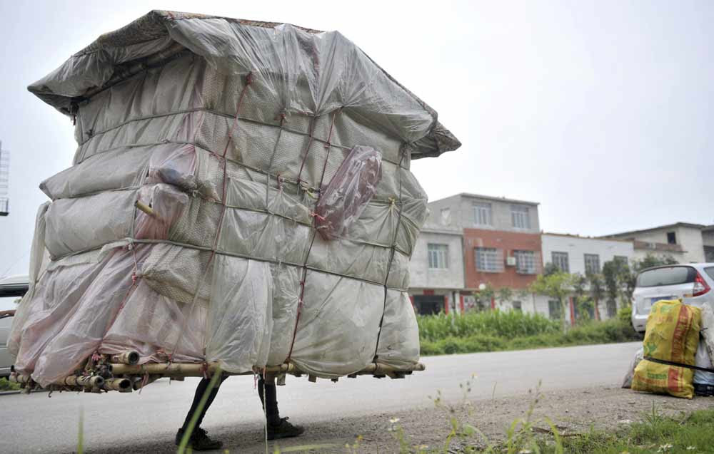 Liu Lingchao, 38, carries his makeshift dwelling as he walks along a road in Shapu township of Liuzhou, Guangxi Zhuang autonomous region. Photo by China Stringer 