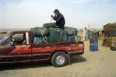 A man sits on top of plastic canisters of petrol that he says was brought from Iran, as he prepares to unload them from a van at a roadside shop near a Pakistan and Iran border