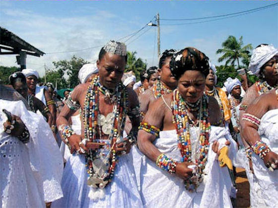 "Le Vodou" mal prononcé et mal orthographié par le Colon, vient du mot "Vodoun", qui signifie en langue Fon : "Ce qu’on ne peut élucider, la puissance efficace". Lequel s’est manifesté dans les entités Mawu et Lissa, incarnations des principes masculin et féminin. De Mawu et Lissa sont nés, selon la légende, quatorze enfants dotés de pouvoirs surnaturels. Ceux-ci ont eu comme descendants : Chango, le Dieu du tonnerre, Nana Bouloukou, la Déesse de la terre, de la nuit et ses mystères, ainsi que Sakpata, le Dieu de la justice et de la propagation de la variole et diverses divinités isolées. Au Bénin, chants et danses sont variés d’Est en Ouest et du Sud au Nord. Selon les circonstances et les évènements, tam-tam, danse, musique et chants peuvent relever à la fois du religieux et du culturel, de la participation aux forces vitales de l’univers, de la louange ou de la simple manifestation de joie, du deuil ou de la communion à l’esprit des morts, de la détente ou du loisir, du simple spectacle chorégraphique, de l’acrobatie et de la véritable expression corporelle, etc. Le culte du vodoun