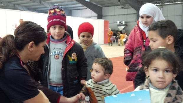 RCMP acting Sgt. Lina Dabit hands out water and colouring books to Syrian refugees in Jordan bound for Canada. 