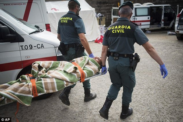Some 600,000 migrants have reached Italy by sea from North Africa since 2014, testing the country's ability to cope. More than 12,000 have died trying. Pictured here, Civil guard members carry an injured migrant to an ambulance at the port of Tarifa, southern Spain, after being rescued with others in the Strait of Gibraltar 