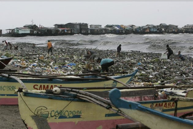 Small outriggers use by fishermen are secured on the shore as people gather salvagable materials from the debris brought by Typhoon Nanmadol Saturday, Aug. 27, 2011 in Manila, Philippines. Forecasters