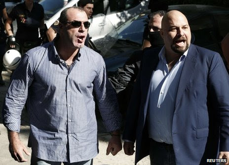 Golden Dawn MPs Ilias Panagiotaros (R) and Nikos Michos shout at media outside court in Athens, 2 October