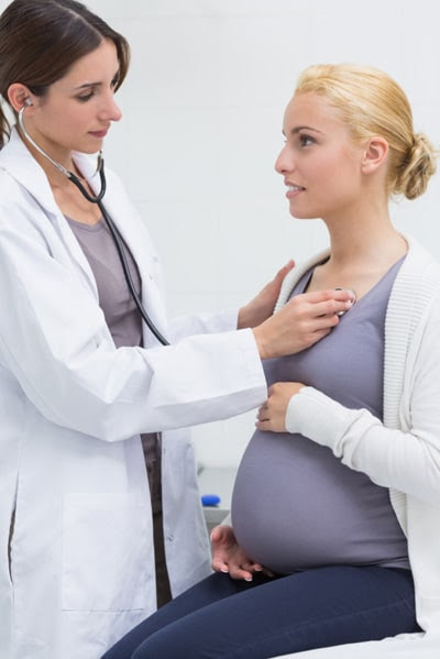 Doctor listening to pregnant woman's heart