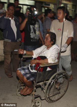 A survivor on a wheelchair is assisted towards a hospital
