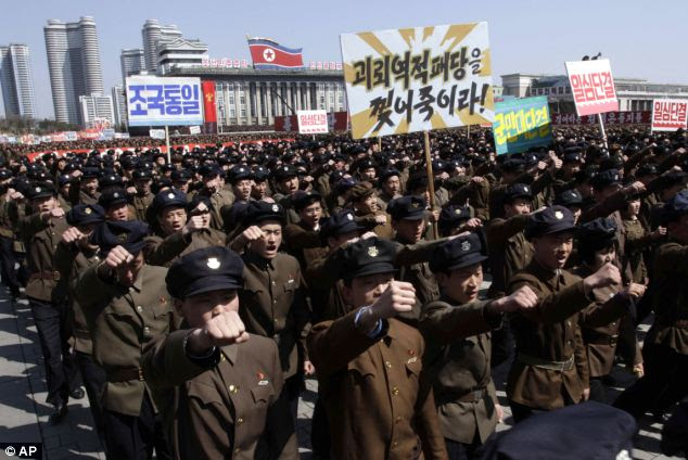 The soldiers and students are shown holding placards that read: 'Reunification of the motherland,' left, and 'Let's rip apart the puppet traitors,' centre